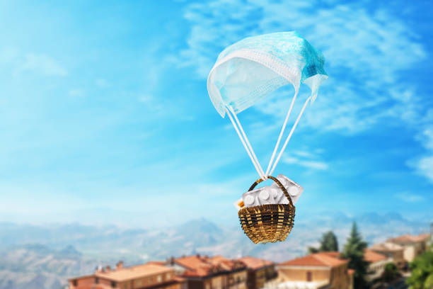 masque médical sous forme d’un parachute et d’un panier avec des pillules sur un fond de ciel. concept d’aide humanitaire - pill container photos et images de collection