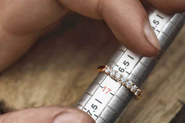 The jeweler checks the size of the gold ring, close-up stock photo