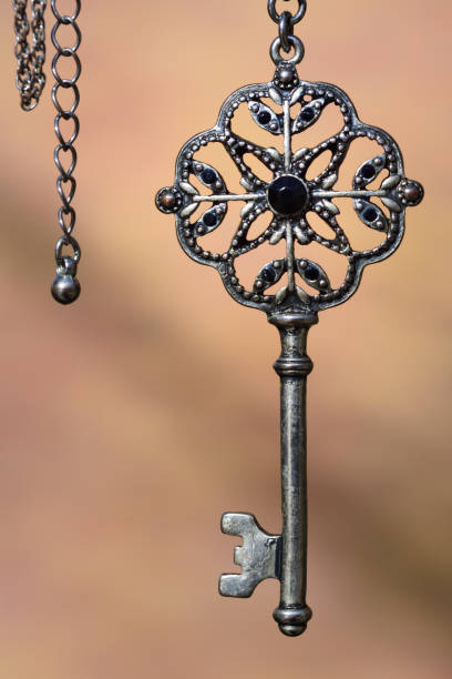 istock An old antique metal key hangs on a silver chain against a light background 1207894990