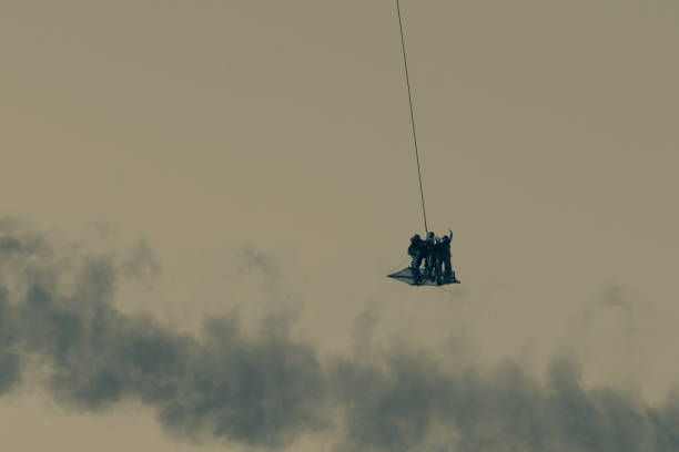militärteam in konflikt rettung menschen mit hubschrauber. fliegen durch die luft auf einem seil am chopper im rauch und dunst im middle east konflikt befestigt. - support horizontal war afghanistan stock-fotos und bilder