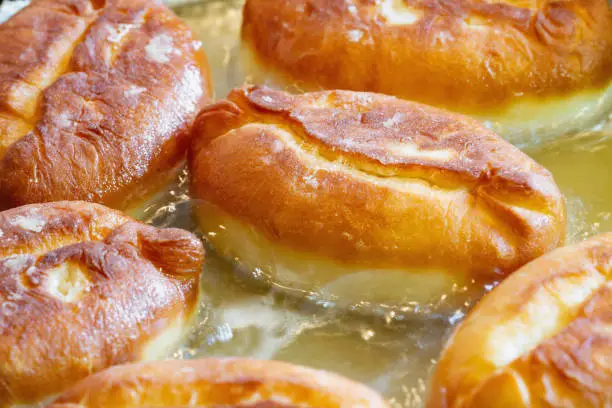 Photo of Homemade pies are deep-fried. Patties from yeast dough are fried in sunflower oil. Closeup, selective focus