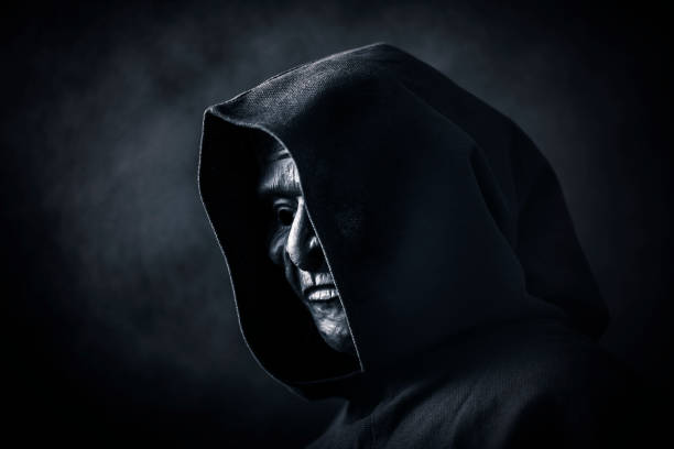 istock Scary figure in hooded cloak with mask 1207900407