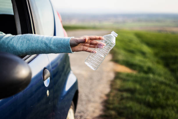 istock Driver throwing away plastic waste from car window on road 1207901513