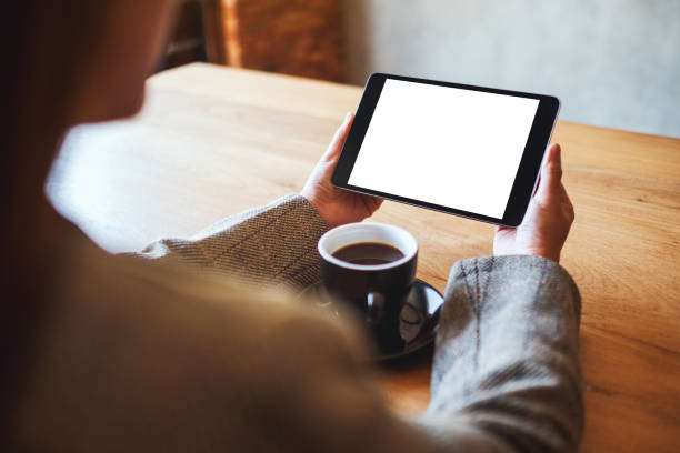 istock woman holding black tablet pc with blank white screen with coffee cup on wooden table 1207904462