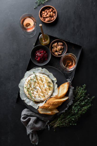 Baked brie served in a rustic manner with honey walnuts cranberry jam and rose wine,top down view Baked brie served in a rustic manner with honey walnuts cranberry jam and rose wine, top down view of dark table setting brie stock pictures, royalty-free photos & images