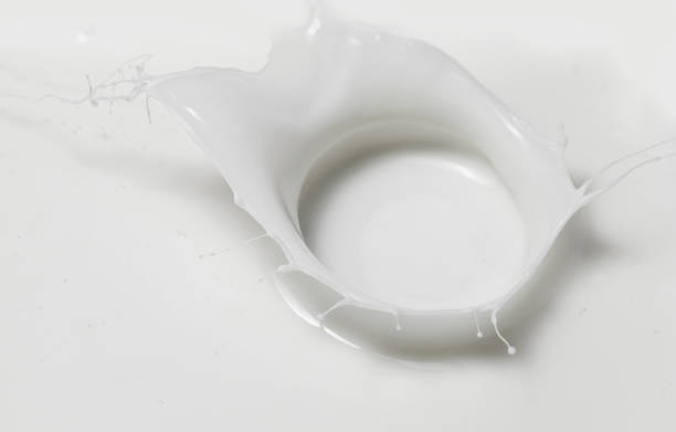 istock Fresh milk pouring making a crown splash in a milk pool. Top view, isolated on grey-white background 1207909945