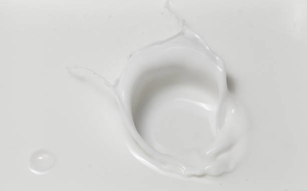 istock Fresh milk pouring making a crown splash in a milk pool. Top view, isolated on grey-white background 1207910014