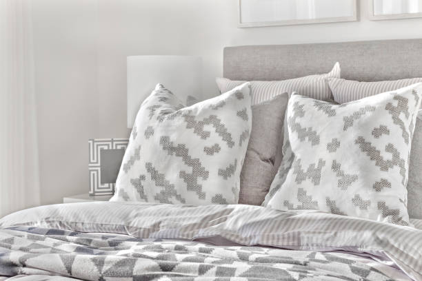 istock Modern bed with pillows and wool blankets near lamps 1207911049