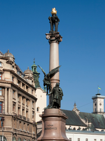 Adam Mickiewicz (famous Polish poet) monument in Lviv, Ukraine. Town Hall with national flag on background. This monument was created by famous Ukrainian sculptor Anton Popiel (1865-1910) in 1904. Popiel created a lot of sculpture projects in Lviv, Krakow and Washington. He was buried on Lichakivske cemetery in Lviv.