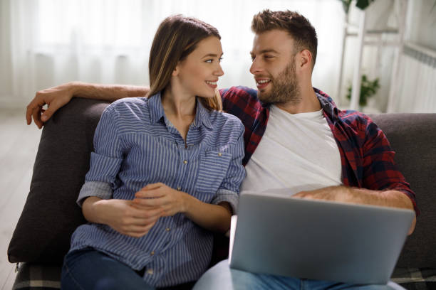 istock Young couple using a laptop while relaxing on the sofa at home 1207921115