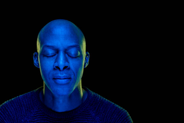 istock Black man with eyes closed. Studio photo with blue light isolated on black background 1207922355