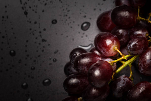 Close up of red grapes on black background with copy space. Water droplets, washing concept
