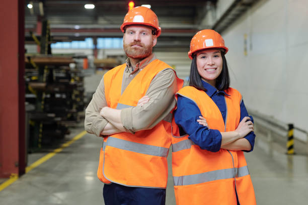 istock Two young successful engineers in hardhats and orange workwear 1207928541
