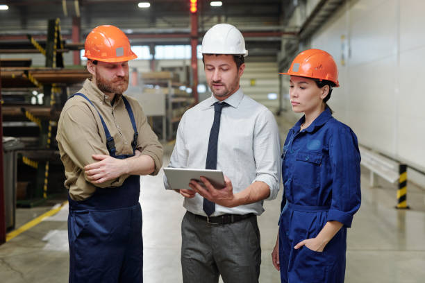 istock Young foreman in hardhat and formalwear making presentation of new project 1207928544