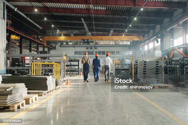 Rear View Of Three Engineers Leaving Workshop At The End Of Working Day Stock Photo - Download Image Now