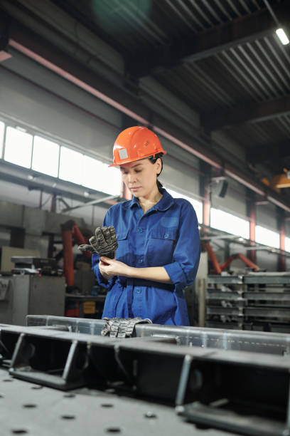 istock Young serious female engineer in workwear putting on gloves before work 1207928611