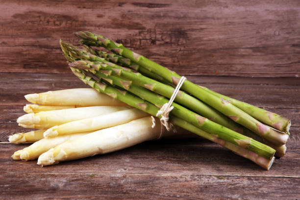 istock White and green asparagus on rustic background. 1207930568