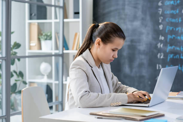 istock Pretty student in grey jacket sitting in front of laptop and entering data 1207932684