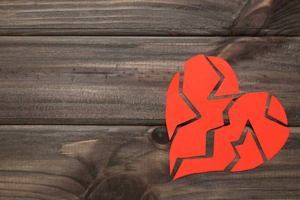 istock Broken paper heart on brown wooden table 1207939498