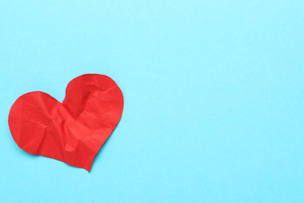 istock Red crumbled paper heart on blue background 1207939518