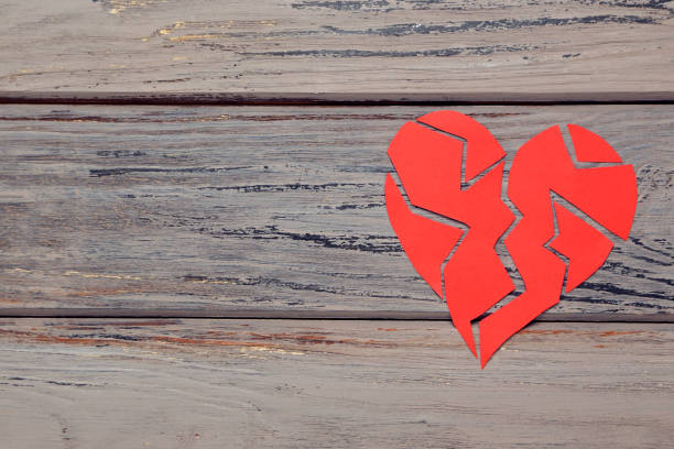 istock Broken paper heart on wooden table 1207941695