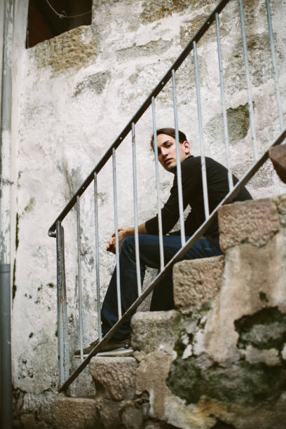 istock Young model man seating on stairs outdoor 1207943744