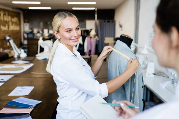 istock Young smiling blond seamstress looking at her colleague during conversation 1207945242