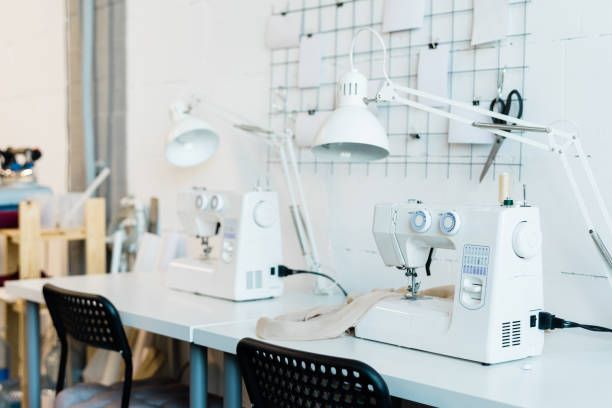 workplace of contemporary seamstress with chair, desk, lamp and sewing machine - textile scientific experiment laboratory textile industry imagens e fotografias de stock