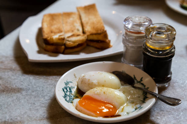 Half boiled eggs, coffee, toast bread, popular Chinese style breakfast in Malaysia Half boiled organic eggs, coffee toast bread, popular Chinese style breakfast in Malaysia kopitiam. Low key lighting. kopitiam egg stock pictures, royalty-free photos & images
