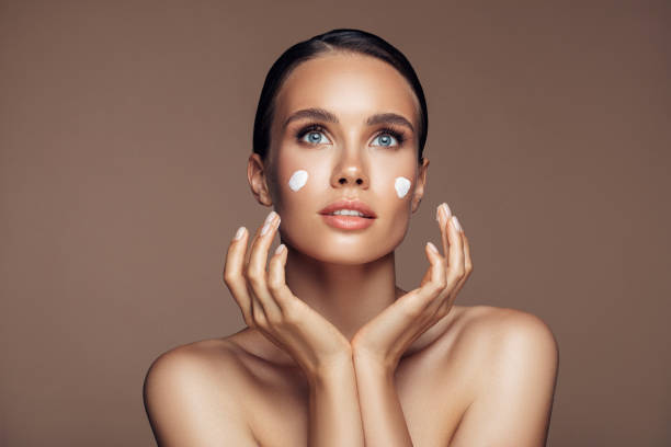 istock Beautiful woman applying cream on her face 1207948174