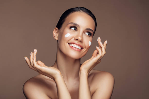 istock Beautiful woman applying cream on her face 1207948215