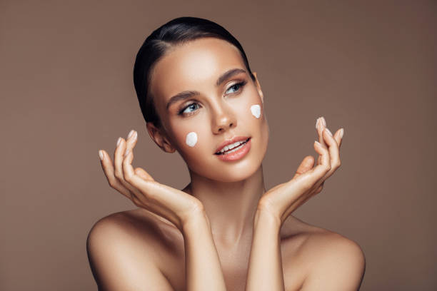 istock Beautiful woman applying cream on her face 1207948256