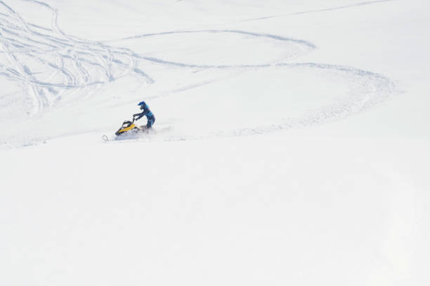 Rider driving snowmobile in deep snow in winter sunny day