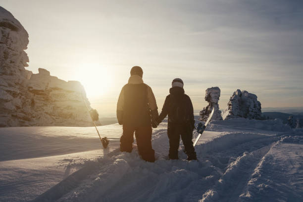 istock Snowboarders with boards walking for freeride in winter mountains and cliffs. Silhouettes on sunset 1207955478