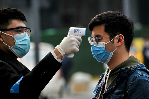 Chengdu/China-Feb.2020: New type coronavirus pneumonia in Wuhan has been spreading into many cities in China. Wearing masks, people lined up for temperature checks before entering the Chunxi Road, downtown mall in Chengdu,China,which is Chengdu's most famous shopping street and has numerous stores for shopping.