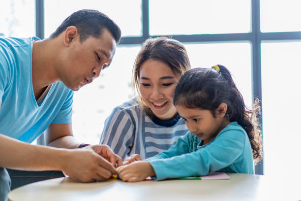 istock Mixed race Asian parents teaching daughter at home 1207956951