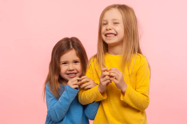 istock Two funny naughty little girls cunningly looking at camera and plotting tricky plan together, scheming excellent idea to prank friend 1207957137