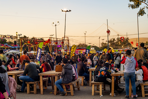 Delhi, India - circa 2020 : Panning shot of crowd of people roaming around sitting on old tables and benches while they eat at the horn ok food truck festival. The various stall around and the huge crowd of men women children can be seen