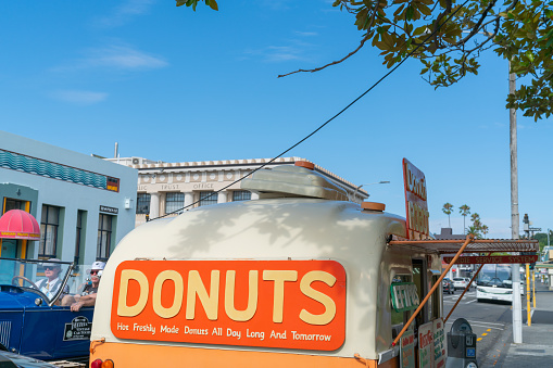 Napier - New Zealand - February 16 2020; Donuts food cart opens in Napier street with large orange colored sign.