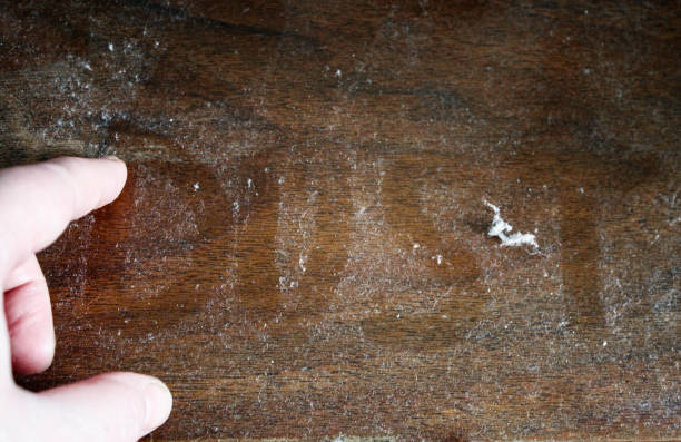 рука пишет слово "пыль" на пыльной деревянной поверхности - house dust allergy стоковые фото и изображения