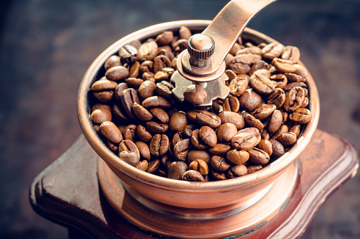 Coffee beans in mill on the rustic wooden background. Selective focus. Shallow depth of field.