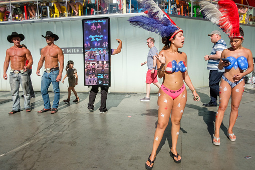 Las Vegas, Nevada, USA - May 13, 2018: Female and male strippers dressed in cowboy and headdress costumes promote their shows outside along the Las Vegas Strip.