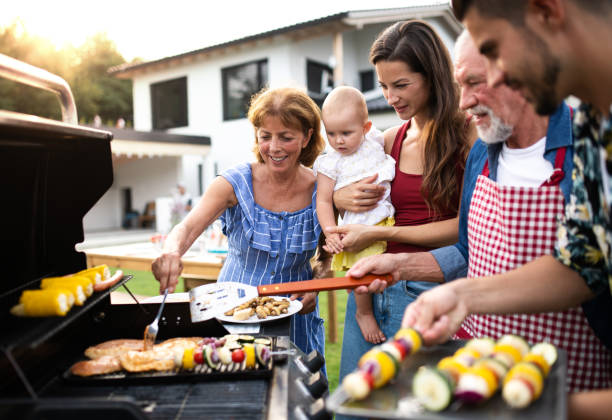 Portrait of multigeneration family outdoors on garden barbecue, grilling. Portrait of multigeneration family outdoors on garden barbecue, grilling and talking. garden parties stock pictures, royalty-free photos & images