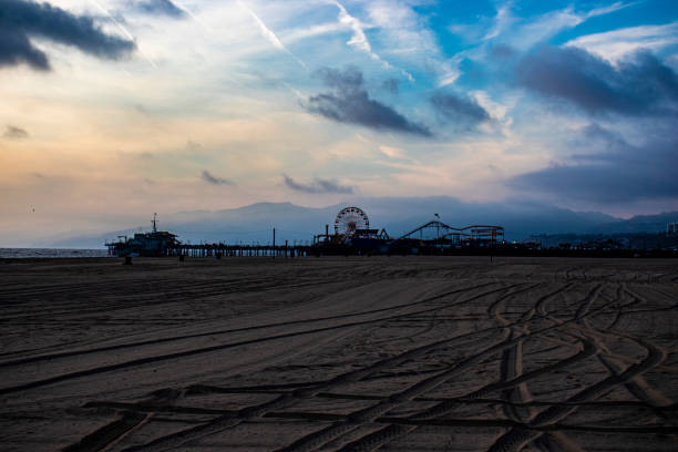 panoramablick auf die promenade und das riesenrad in santa monica kalifornien und den strand mit dem pazifischen ozean, sonnenuntergang und bewölktem himmel horizontales bild - venice california santa monica pier sunset beach stock-fotos und bilder