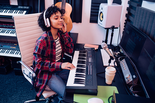 Girl playing keyboards and recording music in the studio