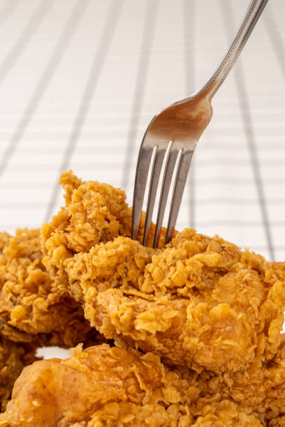 istock Close Up Hand and Fork on Fried Chickens on white Plate Isolated on table. Look Yummy and Yellow Gold Color. 1207976003