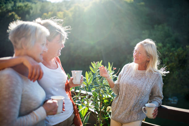 istock Senior women friends standing outdoors on terrace, talking. 1207976301