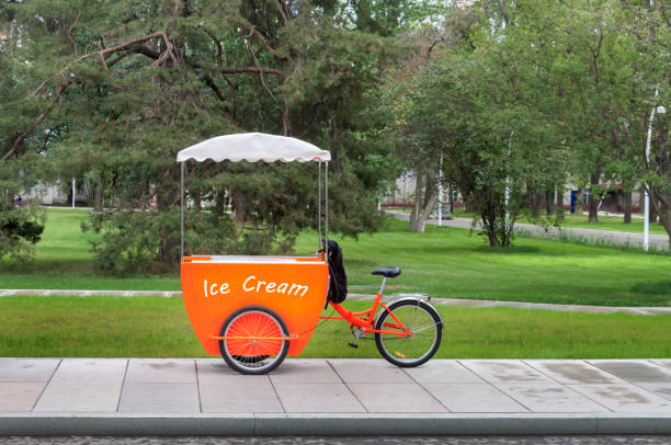 Authentic ice cream orange truck green park tree background warm sunny summer or spring day stock photo