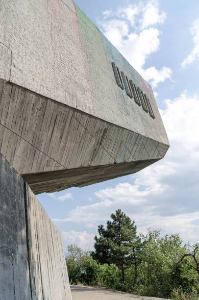 istock Concrete construction with inconspicuous shades of colour upside down, surrounded by a blue sky and a few trees 1207978116