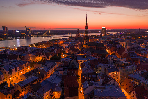Panoramic view of the night city Riga at dusk with a St. Peters Church and river Daugava in the foreground.